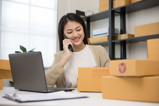 Startup Small business owner entrepreneur. Young asian business woman using mobile phone call receiving purchase order and check product on stock. E-commerce business and shopping online concept.