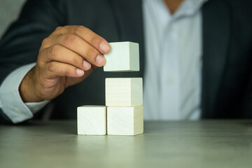 Businessman hand arranging wood cube stacking