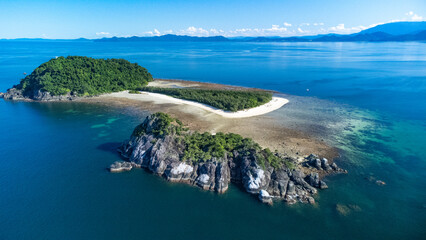 drone footage over a paradise island with healthy coral reef on a sunny day with low wind clear water no waves and good visibility