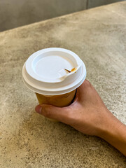 Iced cappuccino or latte in a plastic mug in hand. laid on the old cement floor