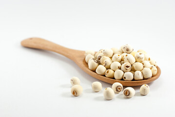 Dried lotus seeds in a wooden ladle and placed on a white floor, selective focus.