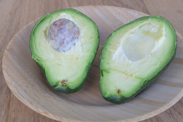 Close up shot an avocado cut in half on a wooden plate - Benefits of avocado concept