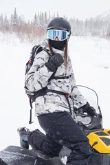 Fotobehang Woman driving snowmobile in winter mountain landscape © Annatamila