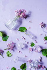 Glass bottles with lilac flowers, pastel colors flat lay, violet still life from above