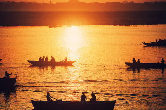 Bright orange sunset on the river, people sitting in boats, a sunny path on the water