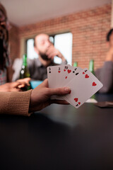 Close up shot of caucasian woman hand holding card games while enjoying fun leisure activity with friends. Person playing card games with people while having snacks and beverages.
