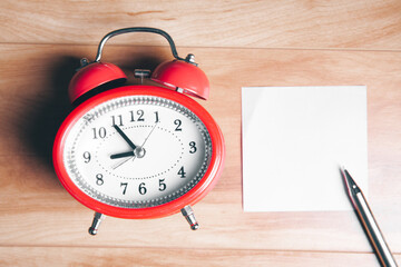 blank note sheet with alarm clock on the table