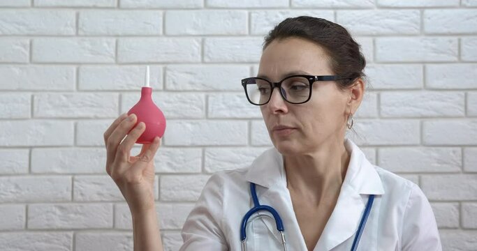 Physician procedure in cabinet. A doctor look an enema in hands for procedure in the room.