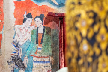 The mural shows a man whispering in the ear of a woman. This mural is a symbol of the famous Wat Phumin