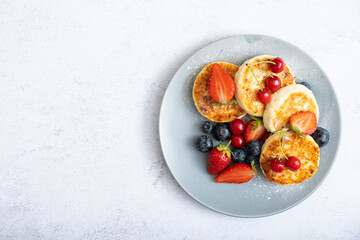 Fried cheesecakes on a plate with berries and powdered sugar top view. Copy space