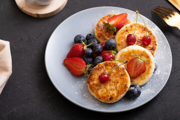 Roasted cheesecakes on a plate with powdered sugar and berries angle view