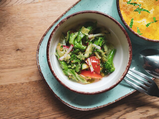 Dietary salad of fresh vegetables: cucumbers, radishes, tomatoes and broccoli, seasoned with olive oil.