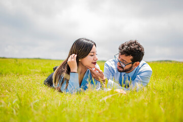 A couple lying on the grass looking at each other, young couple in love lying on the grass touching...