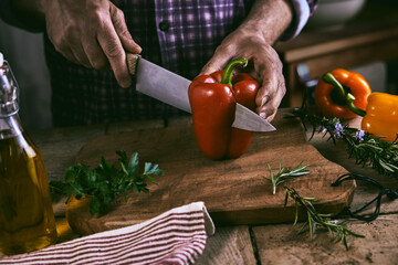 Crop faceless chef cutting bell pepper during dinner preparation