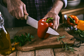 Crop anonymous man preparing dinner with bell pepper and herbs