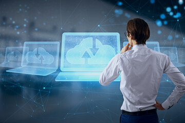 Attractive young caucasian male with abstract polygonal digital laptop with cloud computing hologram on blurry interior background. Database and information concept. Double exposure.