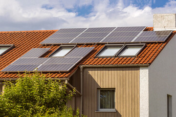 Solar Panel station on private House Roof. Solar panels on tiled roof with windows. 