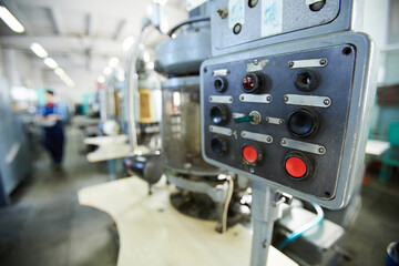 Close-up of control panel of clock movement machine with black and red buttons and small switch