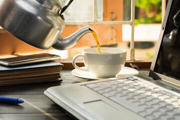 A white coffee cup is placed on the desk. office or at home with a notebook computer keyboard tablet pc