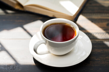 White coffee cup with black coffee or tea. put on desk or reading table - top view