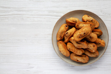 Homemade Chocolate Chips Madeleines on a Plate on a white wooden surface, top view. Flat lay, overhead, from above. Copy space.