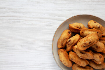Homemade Chocolate Chips Madeleines on a Plate on a white wooden surface, top view. Flat lay, overhead, from above. Space for text.