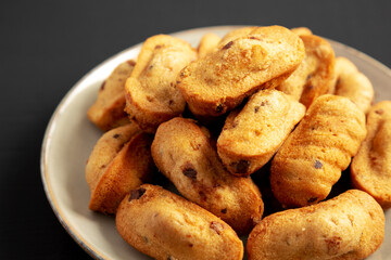 Homemade Chocolate Chips Madeleines on a Plate on a black background, side view. Close-up.