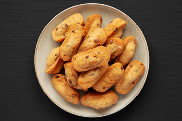 Homemade Chocolate Chips Madeleines on a Plate on a black background, top view. Flat lay, overhead, from above.