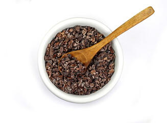 Cocoa nibs, a pieces of broken cocoa beans in a white bowl isolated on white.