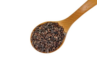 Cocoa nibs, a pieces of broken cocoa beans in a wooden spoon isolated on white background.