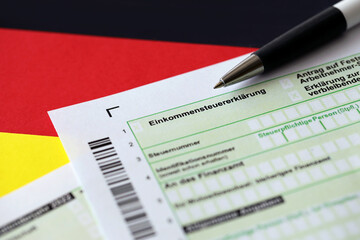German annual income tax return declaration form with pen on flag close up. The concept of tax...