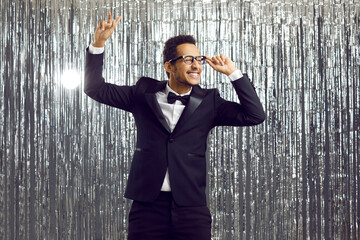 Cheerful mixed race guy in elegant tuxedo outfit having fun at nightclub disco party. Happy funny...