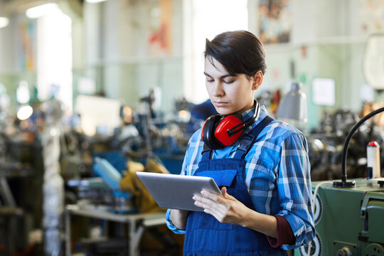 Serious Thoughtful Lady Worker With Short Black Hair Standing In Factory Shop Of Watch Plant And Checking Information On Tablet