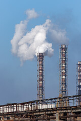 Smoke stack of coal power plant on blue sky background.