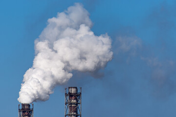 Smoke stack of coal power plant on blue sky background.