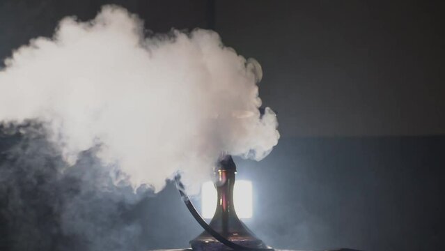clouds of smoke overwhelm the hookah standing in the backlight