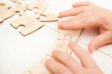 3D wooden toy. Learning letters in order of alphabet. Child's fingers holds pieces of unfinished to assemble puzzle.