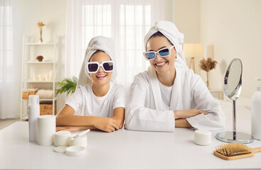Portrait of happy good looking mother and pretty little daughter wearing bath towels and trendy...