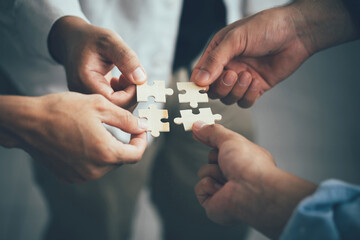 Concept of teamwork and partnership. Hands join puzzle pieces in the office. business people putting the jigsaws team together.Charity, volunteer. Unity, team business. - obrazy, fototapety, plakaty