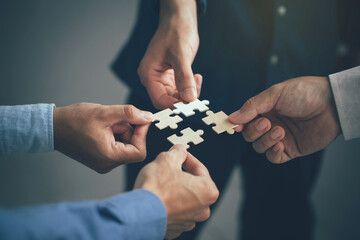 Concept of teamwork and partnership. Hands join puzzle pieces in the office. business people...