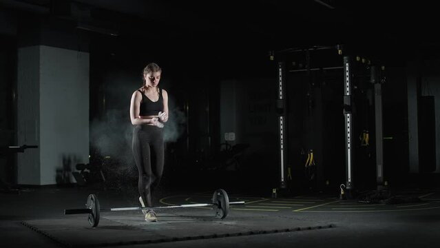 Female fighter performs a deadlift with barbell, lifts barbell and does weights training in the gym, woman power.