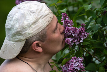the guy in the cap sniffs lilac