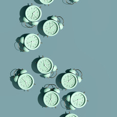 Top view of creative pattern made of red alarm clocks on a blue background