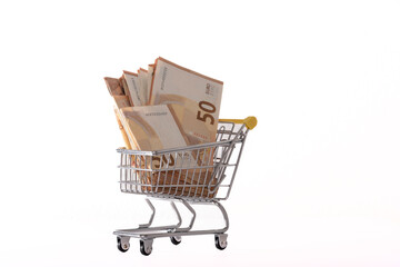 Toy supermarket cart or shopping trolley with money isolated on white background close-up.