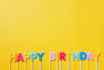 party background with text Happy Birthday by colorful candles on orange backround. Happy birthday...