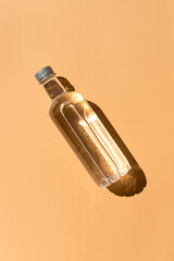 Transparent plastic bottle of water close up top view on the sunny orange background