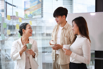 Friendly executive business leader having discussion with young employees at coffee break in office