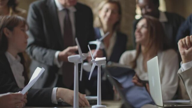 model windmill turbines in motion - professor in the background giving less to young engineers students