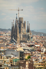 View of the Sagrada Familia cathedral still under construction, surrounded by buildings, in Barcelona, Spain