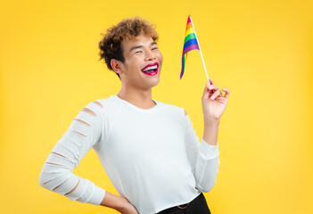 Transgender female smiling and holding a pride flag isolated yellow background, Pride month LGBTQ...